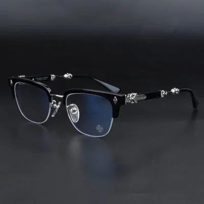 Black browline spectacle frames with clear lenses and engraved metal detailing on the temples, on a dark background