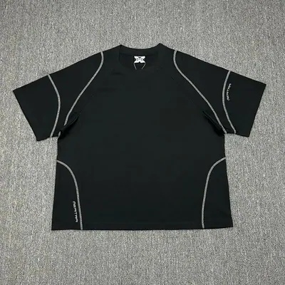 A black short sleeved technical t-shirt on a grey surface, with contrast seam lines running over the shoulders and sides