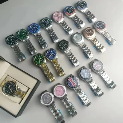 Around fifteen steel bracelet watches laid out on a white surface, with one more in an open presentation box